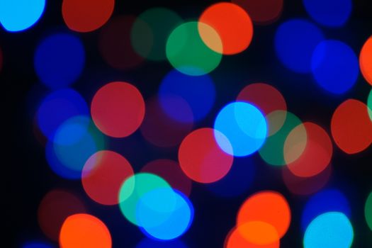 Multi-color blue holiday garland. Garland is blurred. Many big colorful round lights. Fully defocused photo. Blurred background and foreground. Holiday mood. New Year and Christmas is coming.