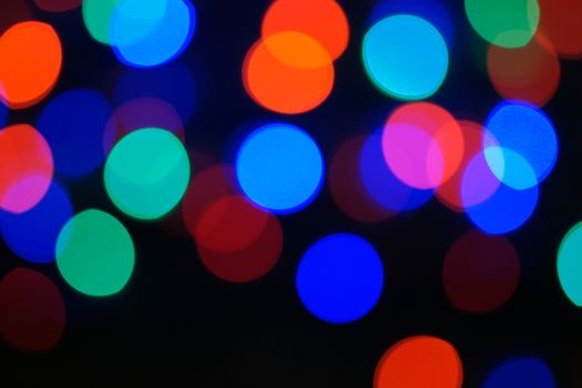 Multi-color blue holiday garland. Garland is blurred. Many big colorful round lights. Fully defocused photo. Blurred background and foreground. Holiday mood. New Year and Christmas is coming.