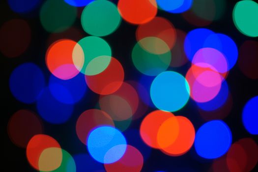 Multi-color blue holiday garland. Garland is blurred. Many big colorful round lights. Fully defocused photo. Blurred background and foreground. Holiday mood. New Year and Christmas is coming.