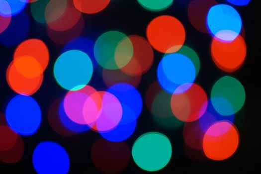 Multi-color blue holiday garland. Garland is blurred. Many big colorful round lights. Fully defocused photo. Blurred background and foreground. Holiday mood. New Year and Christmas is coming.