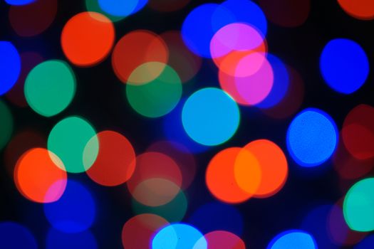 Multi-color blue holiday garland. Garland is blurred. Many big colorful round lights. Fully defocused photo. Blurred background and foreground. Holiday mood. New Year and Christmas is coming.