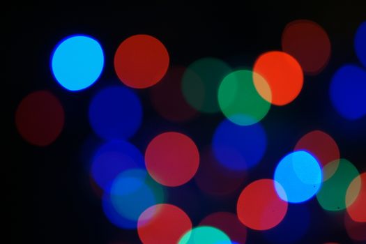 Multi-color blue holiday garland. Garland is blurred. Many big colorful round lights. Fully defocused photo. Blurred background and foreground. Holiday mood. New Year and Christmas is coming.
