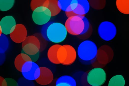 Multi-color blue holiday garland. Garland is blurred. Many big colorful round lights. Fully defocused photo. Blurred background and foreground. Holiday mood. New Year and Christmas is coming.