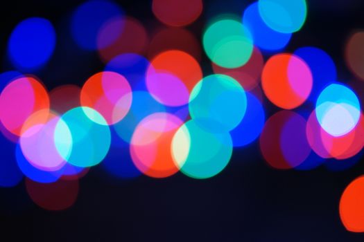 Multi-color blue holiday garland. Garland is blurred. Many big colorful round lights. Fully defocused photo. Blurred background and foreground. Holiday mood. New Year and Christmas is coming.