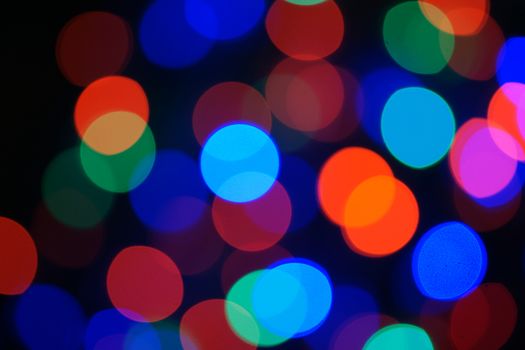 Multi-color blue holiday garland. Garland is blurred. Many big colorful round lights. Fully defocused photo. Blurred background and foreground. Holiday mood. New Year and Christmas is coming.