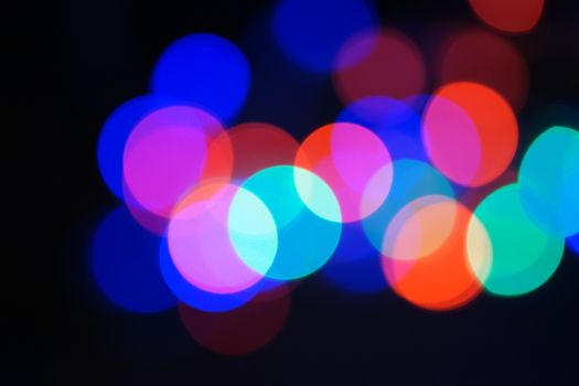 Multi-color blue holiday garland. Garland is blurred. Many big colorful round lights. Fully defocused photo. Blurred background and foreground. Holiday mood. New Year and Christmas is coming.