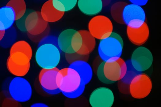 Multi-color blue holiday garland. Garland is blurred. Many big colorful round lights. Fully defocused photo. Blurred background and foreground. Holiday mood. New Year and Christmas is coming.