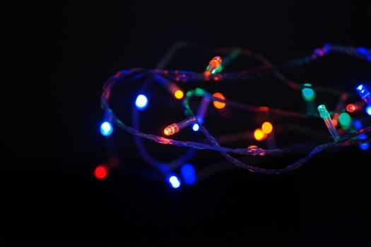 Multi-color blue holiday garland. Garland is blurred. Many big colorful round lights. Fully defocused photo. Blurred background and foreground. Holiday mood. New Year and Christmas is coming.