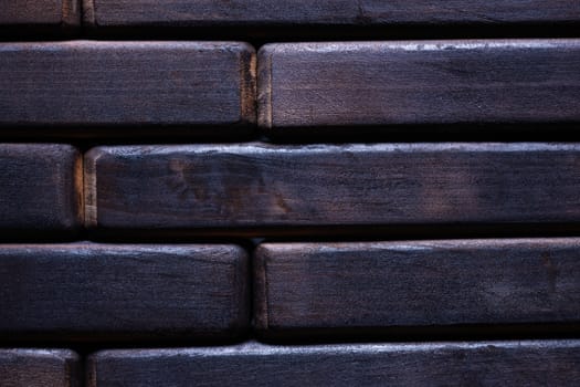 Dark black wooden background. Floor contains wooden bricks. Closeup view.