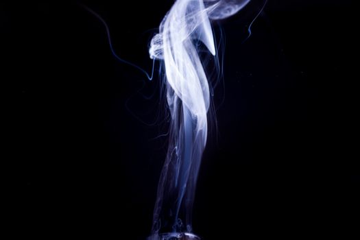 Vape smoke clouds isolated on black background. Hot vape liquid splash in vape coil. Nice aromatic cloud. Low light photo. Underexposed photo in a low key style.