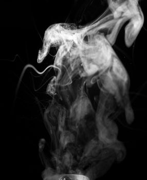 Vape smoke clouds isolated on black background. Hot vape liquid splash in vape coil. Nice aromatic cloud. Low light black and white monochrome photo. Underexposed photo in a low key style.