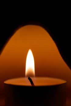 Underexposed low light photo of candle in aromatic lamp. Close-up view