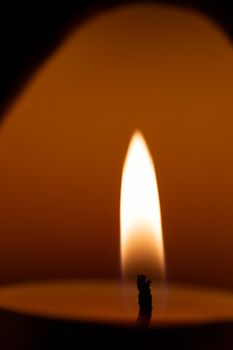 Underexposed low light photo of candle in aromatic lamp. Close-up view