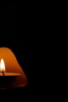 Underexposed low light photo of candle in aromatic lamp. Close-up view