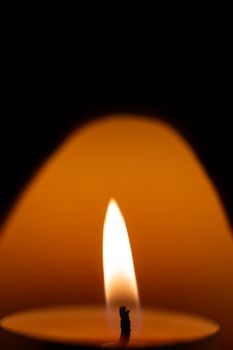 Underexposed low light photo of candle in aromatic lamp. Close-up view