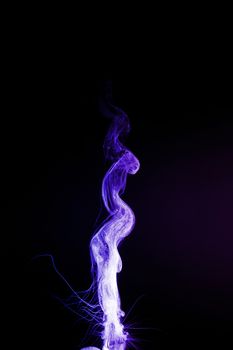 Dual colour vape steam column with spray boiling liquid. Blue and purple colour smoke. Stock photo isolated on black background.