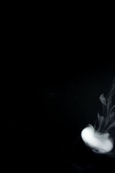 Round ring of vape fog on black background. At right side thick smoke ring goes down.. Vape culture and no smoking direction.