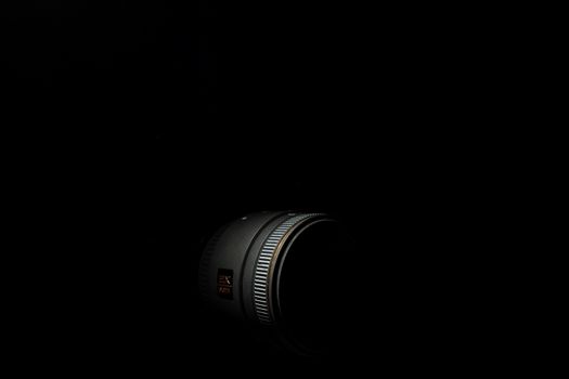 Ukraine; Kyiv; 20.02.2019 Sigma 50mm f1:2,8 DG EX Macro lens. Underexposed photo of DSLR camera lens on black background. Stock photo isolated. Low light photo and large depth of field.