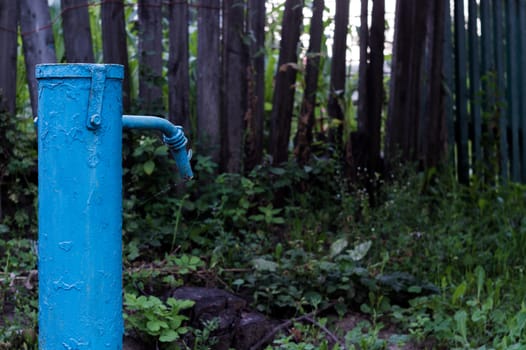 The blue broken water hydrant. Paint is very old and cracked.