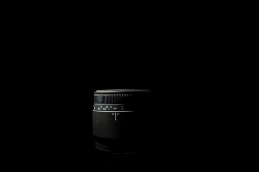 Underexposed photo of DSLR camera lens lying on black background. Stock photo isolated. Low light photo and large depth of field.