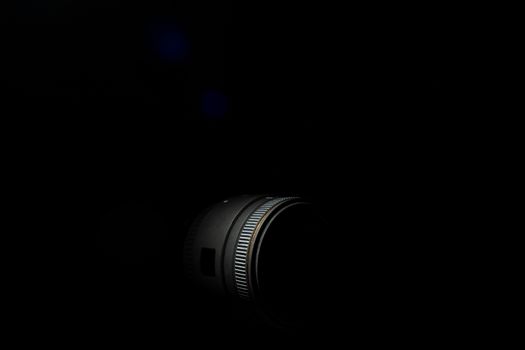 Underexposed photo of DSLR camera lens. Stock photo isolated on black background. Low light photo and large depth of field.