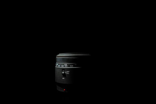Underexposed photo of DSLR camera lens lying on black background. Stock photo isolated. Low light photo and large depth of field.