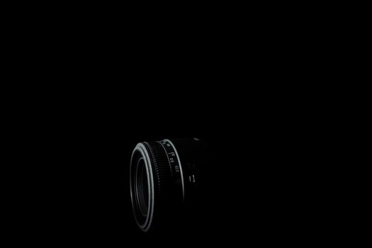 Underexposed photo of DSLR lens. Stock photo isolated on black background. Low light photo. A large depth of field.