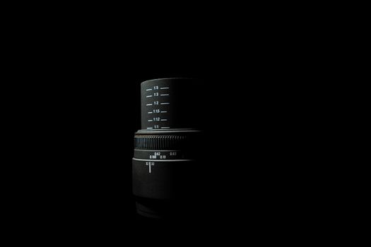 Underexposed photo of DSLR camera lens lying on black background. Stock photo isolated. Low light photo and large depth of field.