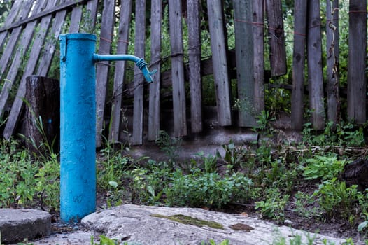 The blue broken water hydrant. Paint is very old and cracked.