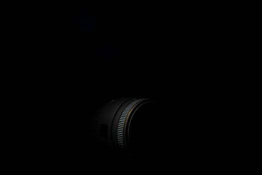 Underexposed photo of DSLR camera lens. Stock photo isolated on black background. Low light photo and large depth of field.