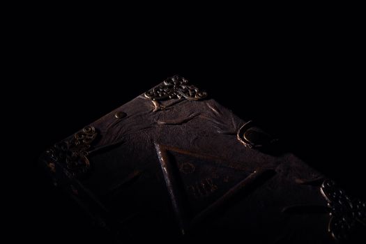Low light old handmade leather cover notebook. Old leather cover isolated on black background. Underexposed stock photo.