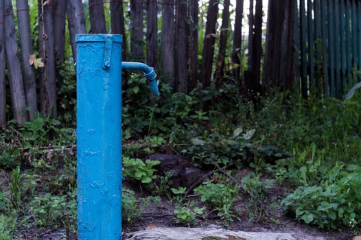 The blue broken water hydrant. Paint is very old and cracked.