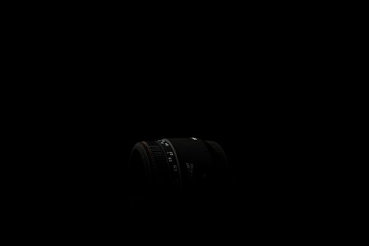 Underexposed photo of DSLR lens. Stock photo isolated on black background. Low light photo. A large depth of field.