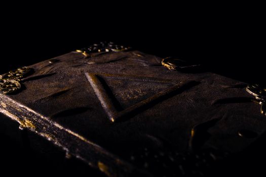 Low light old handmade leather cover notebook. Old leather cover isolated on black background. Underexposed stock photo.