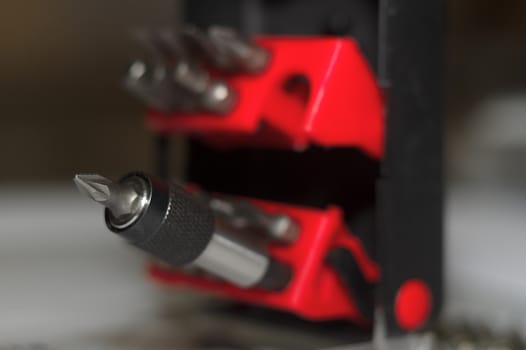 Bits holder in box and many tool bits on white background. Close-up view. Red element in plastic box.