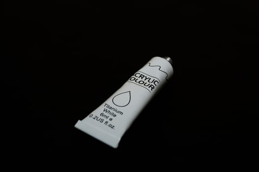 Acrylic white titanium paint metal tube on black background. New tube. Aluminium tube of paint.