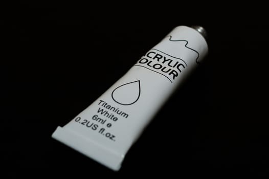Acrylic white titanium paint metal tube on black background. New tube. Aluminium tube of paint.