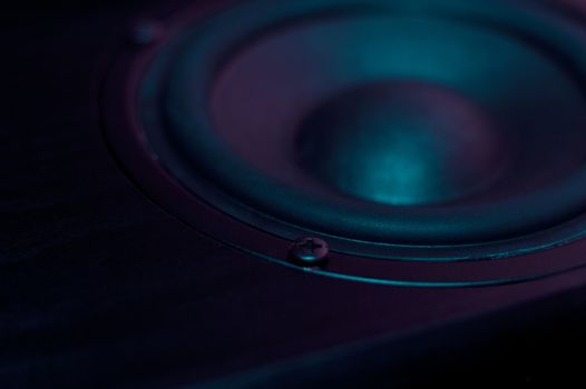 Professional loudspeaker from acoustic system in purple colours. Woofer and midbass speaker on photo. Night club atmosphere.