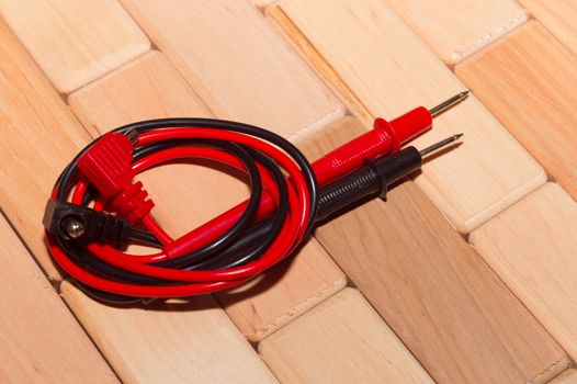 probes of a digital multimeter on the floor of wooden planks