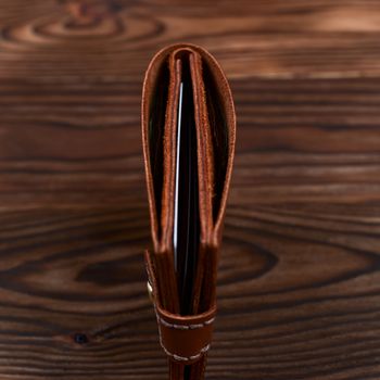 Handmade leather gloss wallet on wooden textured background. Businessman wallet stock photo.