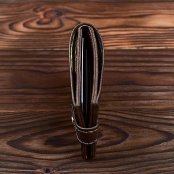 Handmade leather gloss wallet on wooden textured background. Businessman wallet stock photo.