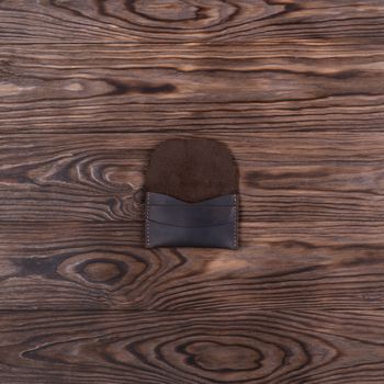 Flat lay photo of brown colour handmade leather one pocket cardholder. Stock photo on wooden background.