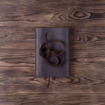 Brown handmade leather notebook cover with notebook on wooden background. Stock photo of luxury business accessories. Up to down view.