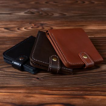 Three handmade leather wallets on wooden textured background. closeup. Wallet stock photo.