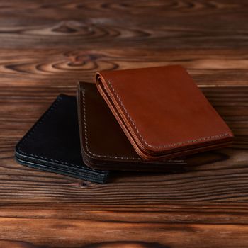 Three handmade leather wallets on wooden textured background. closeup. Wallet stock photo.