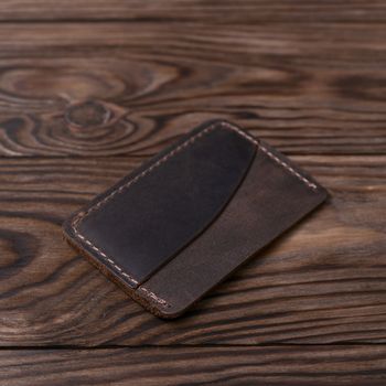Brown colour handmade leather one pocket cardholder on wooden background. Stock photo with soft blurred background.