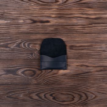 Flat lay photo of black colour handmade leather one pocket cardholder. Stock photo on wooden background.