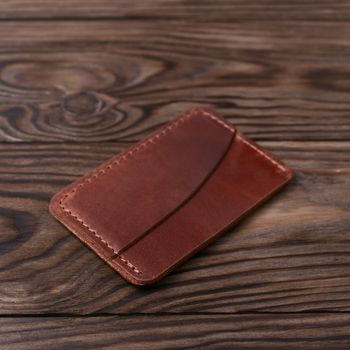 Ginger colour handmade leather one pocket cardholder on wooden background. Stock photo with soft blurred background.