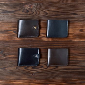 Four handmade leather gloss wallets on wooden textured background. Up to down view. Businessman wallet stock photo.