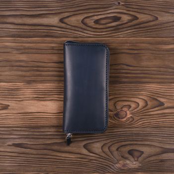 Mattle black color handmade leather porte-monnaie on wooden textured background.  Up to down view. Stock photo of luxury accessories.
